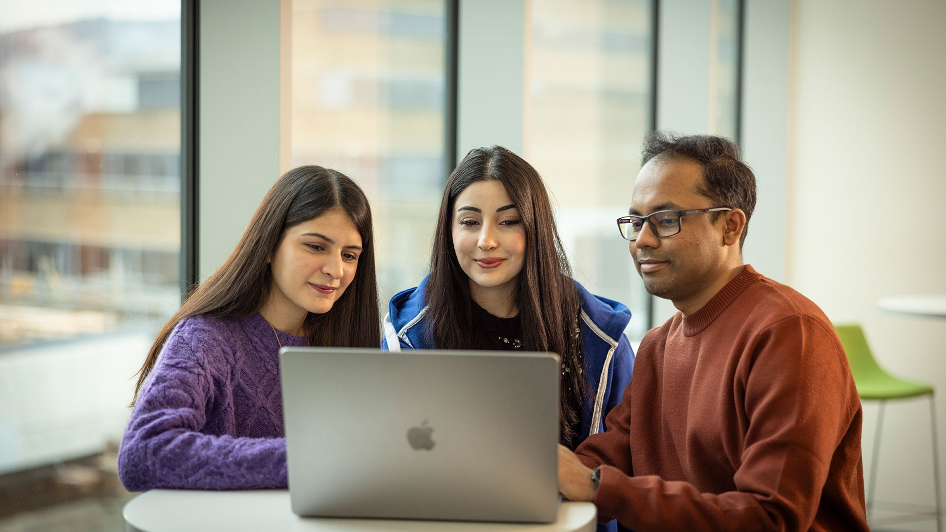 Three students working on a laptop