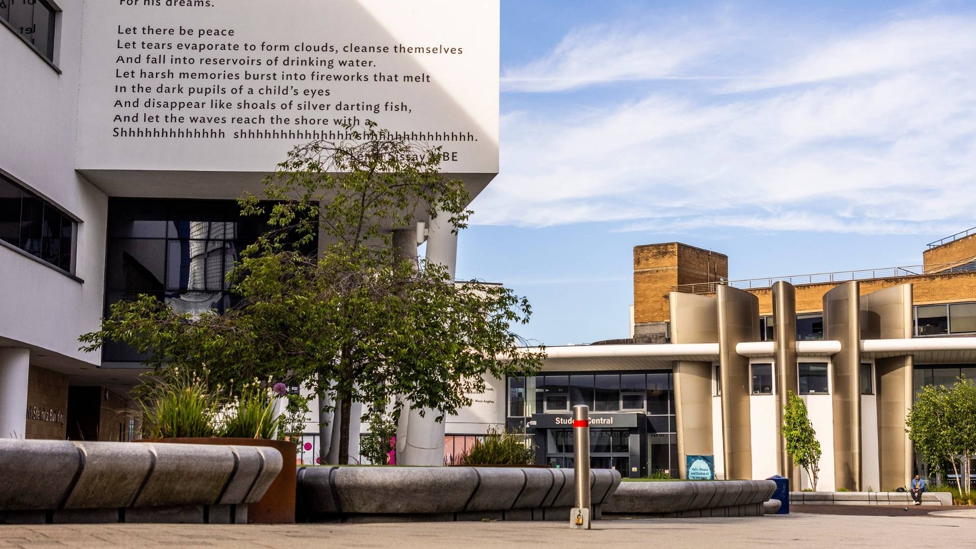 A paved area surrounded by buildings of different styles against a blue sky