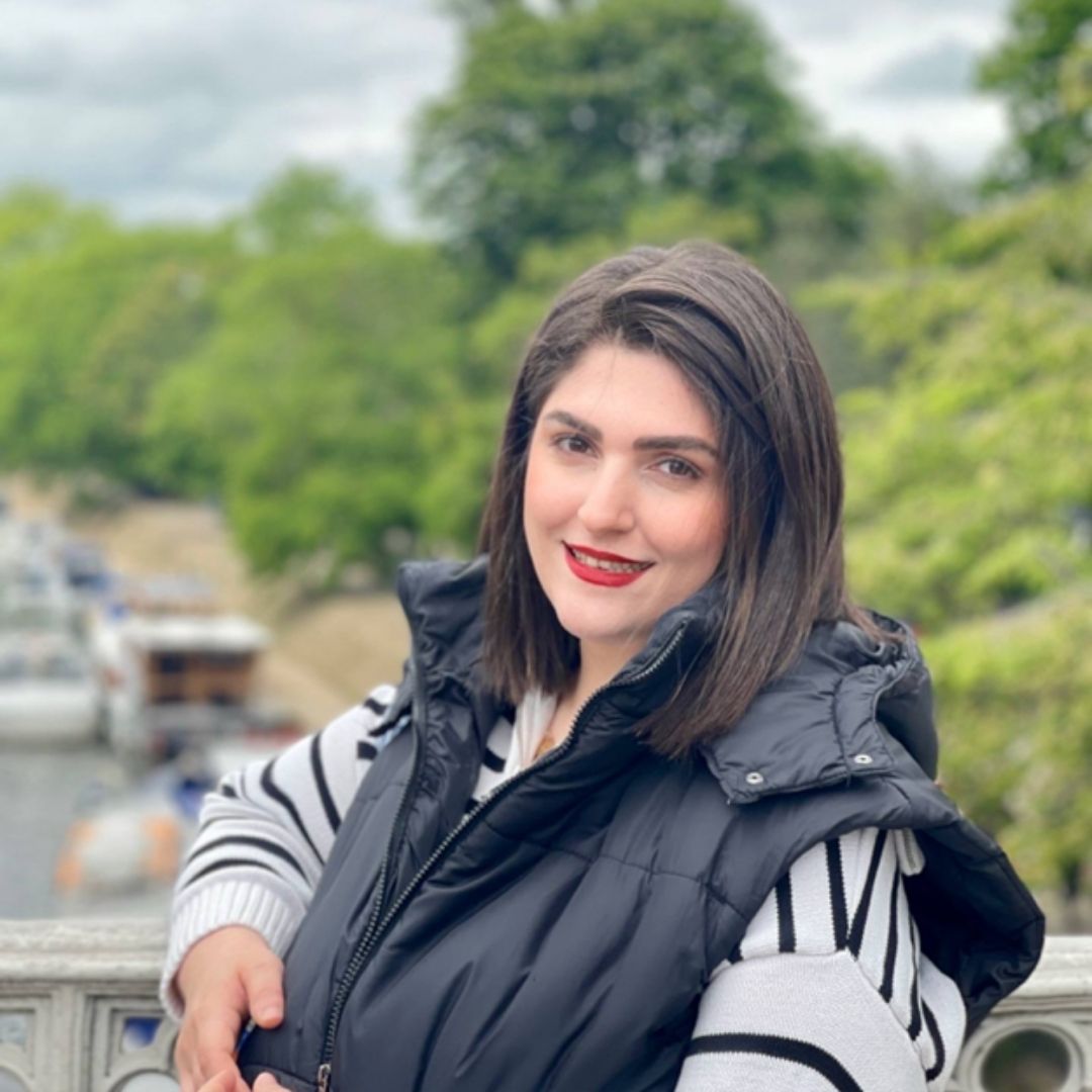 Pegah leaning outside, wearing a black jacket