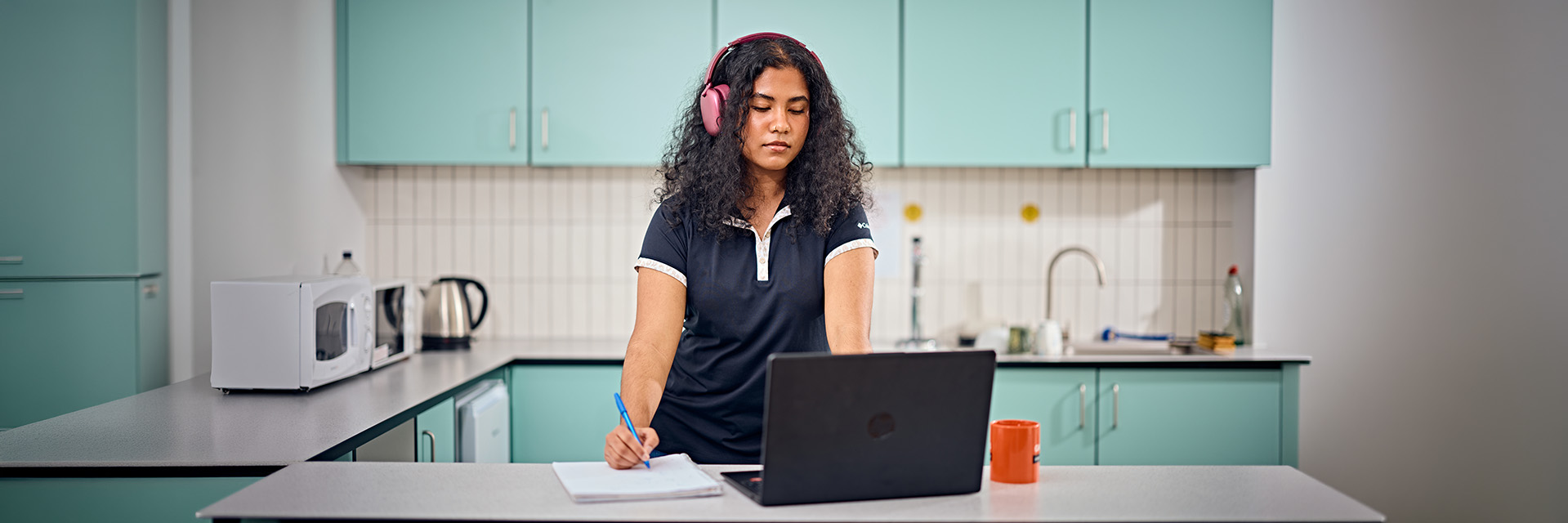 International student working on a laptop in a kitchen