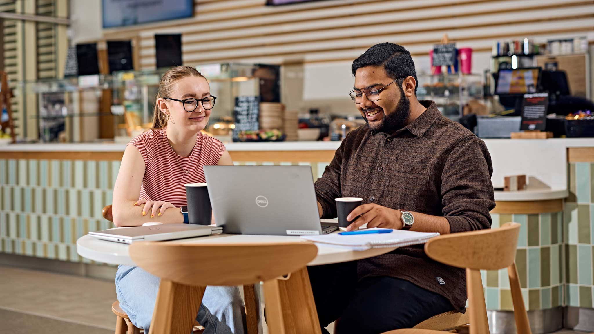 Students chatting over a laptop in a cafe