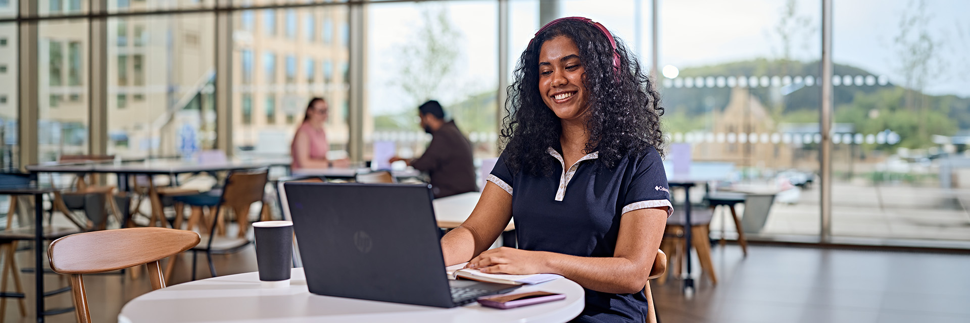 Student working in a cafe smiling