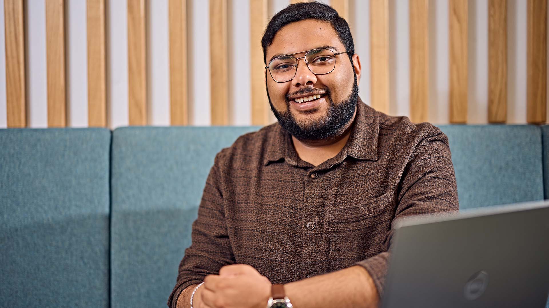 Student smiling in a working area with a laptop