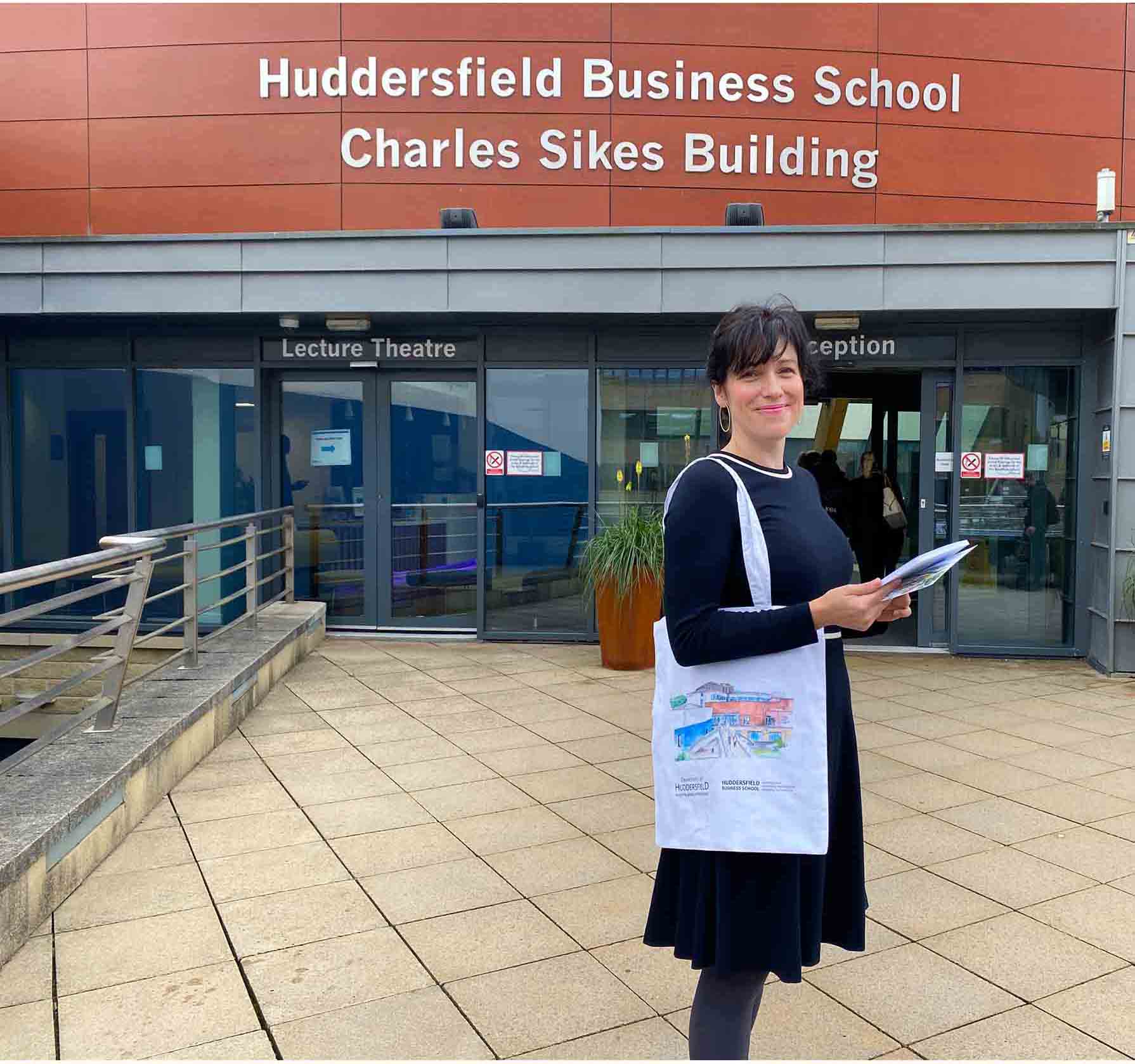 Emily stood outcome Huddersfield Business School smiling with the new marketing collateral