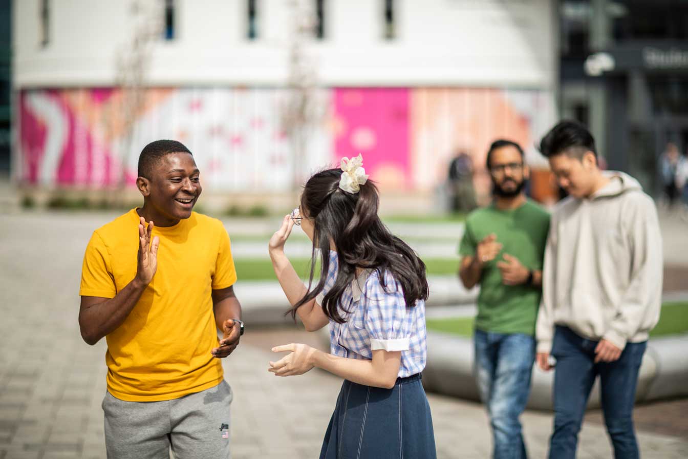 Students waving outside of student central building