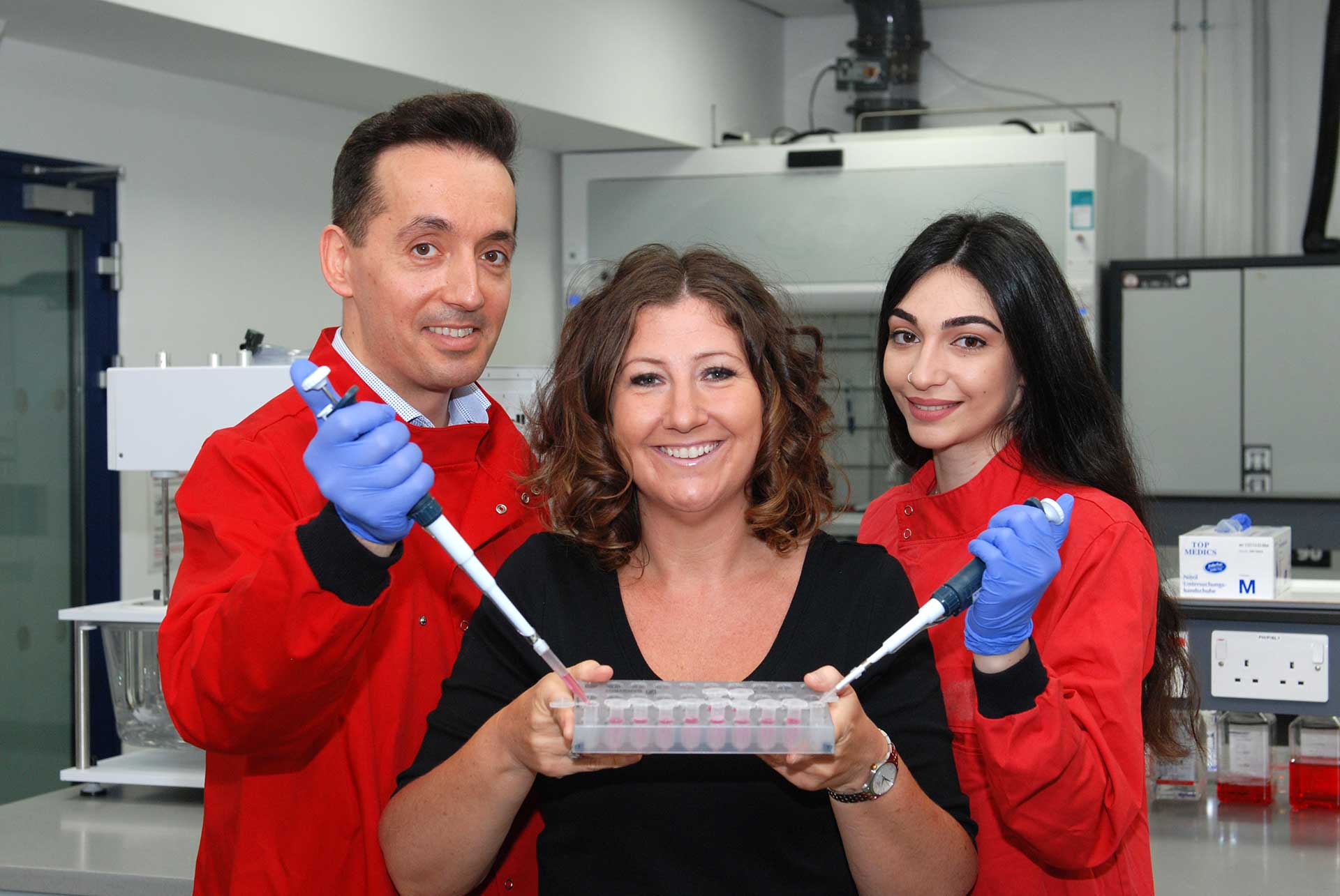 Dr Nik Georgopoulos, Fundraising Manager Helen Mervill from the Laura Crane Youth Cancer Trust and PhD Researcher Myria Ioannou lowering pipettes into a specimen tray