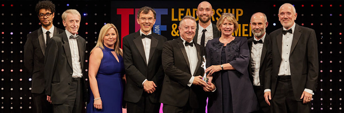 University of Huddersfield's Vice-Chancellor, Professor Bob Cryan (centre) receives the award from Alison Johns, CEO of AdvanceHE.  Also pictured (l-r) are Richard Ayoade, Colin Blair, Siobhan Campbell, Professor Tim Thornton, Danny Benton, Matt Mills and Andrew McConnell