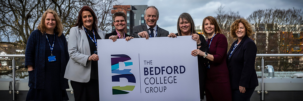 A group of people holding a banner with The Bedford College Group logo