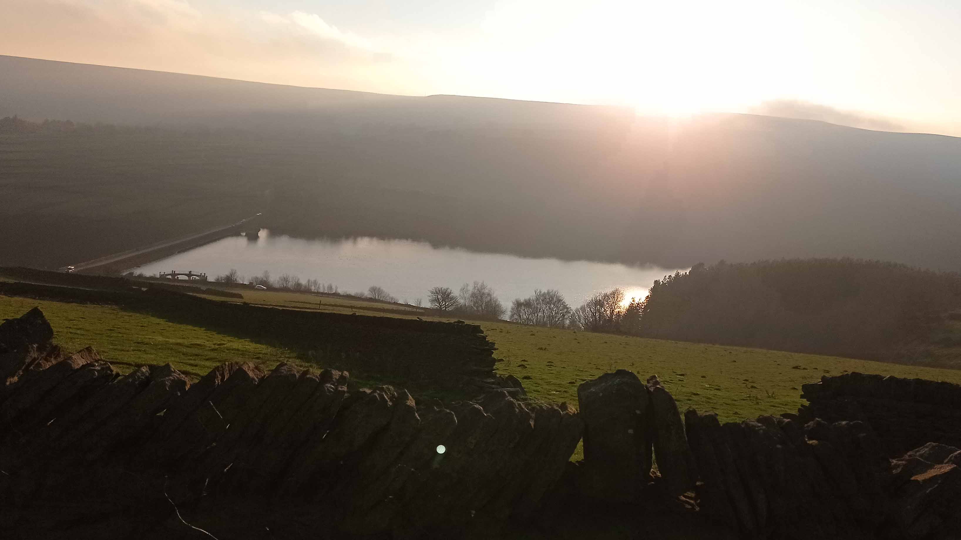 A reservoir with the sun rising above it