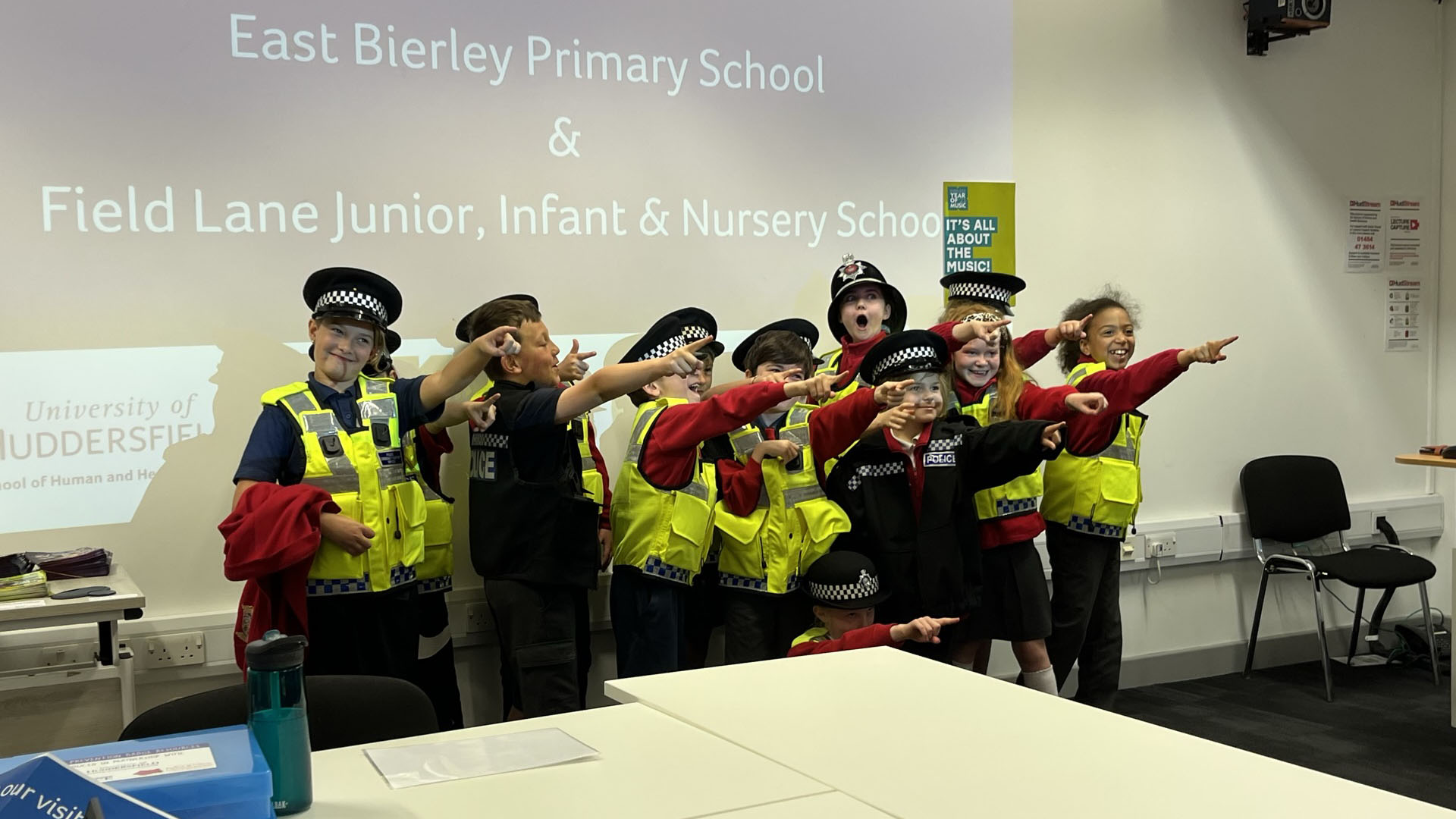 Children wearing police uniform laugh and point at the camera