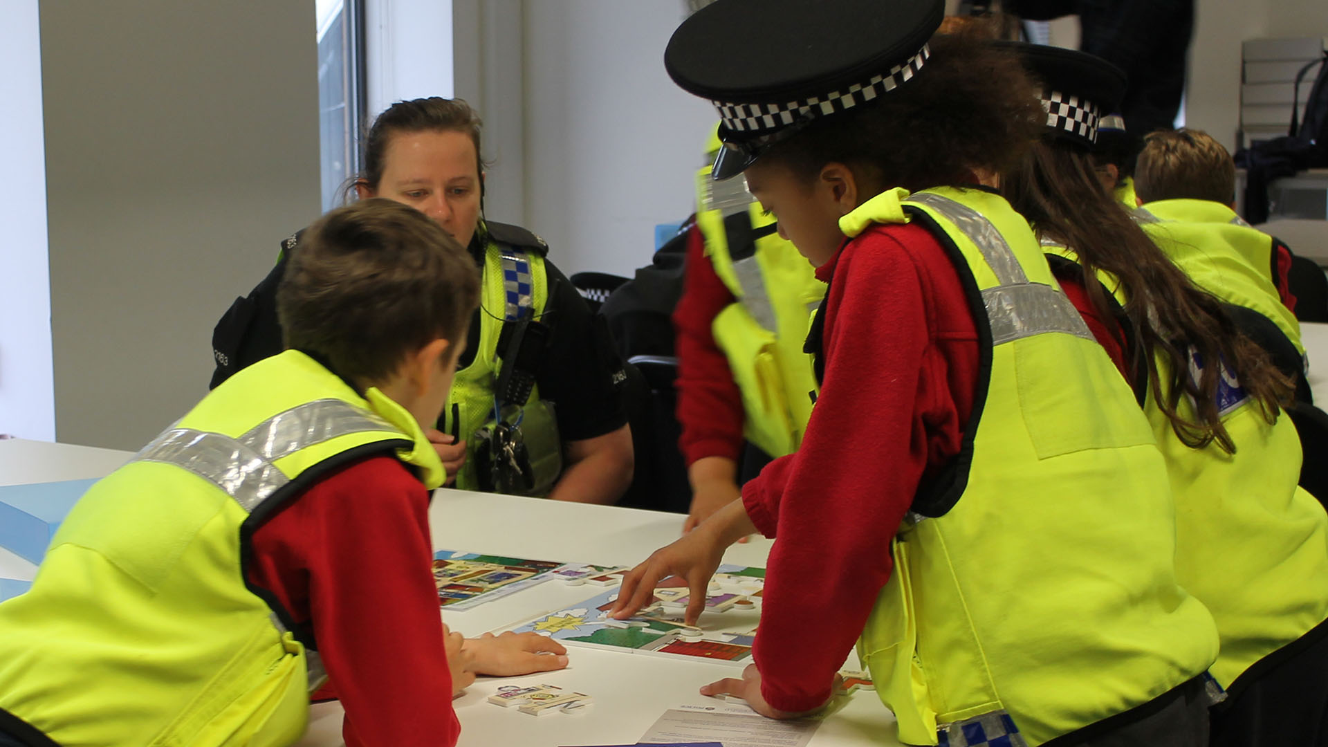 Some children do a jigsaw puzzle with a female police officer