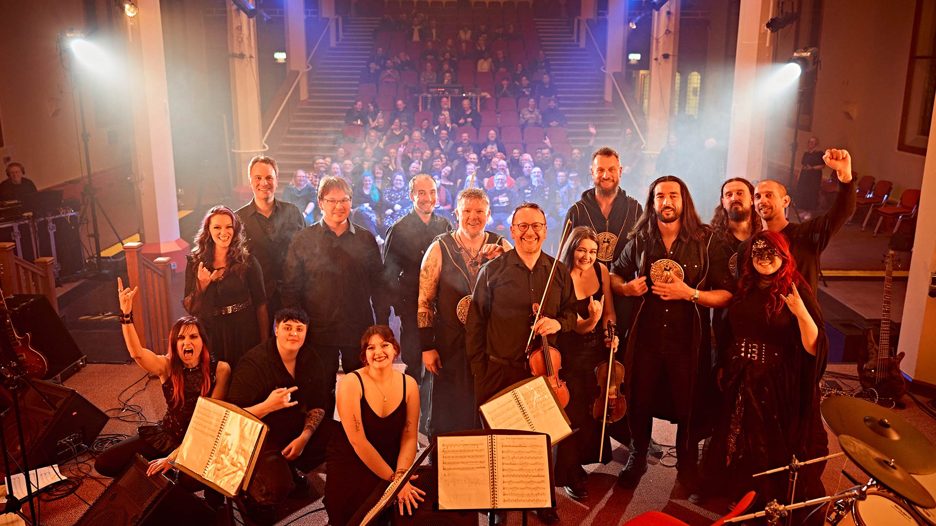 A metal band and pipe organ on stage at St Paul's Hall in Huddersfield with audience in background