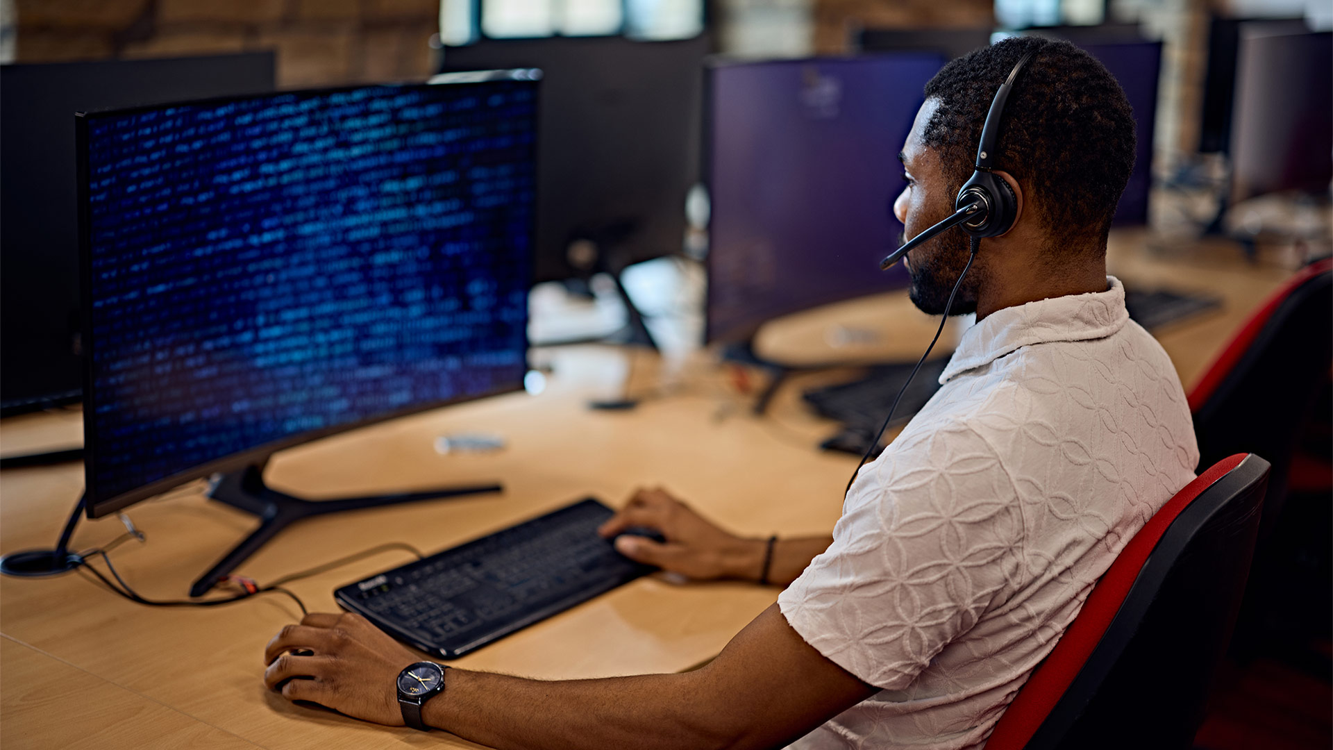 a student sat at a computer wearing headphone