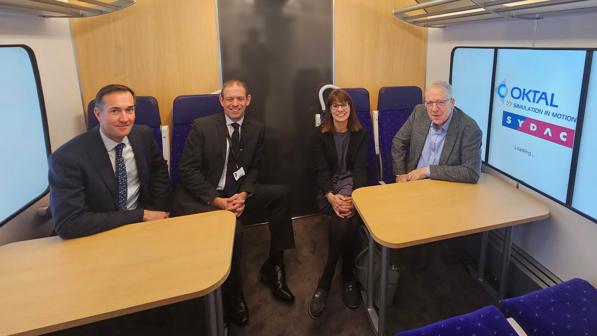 A group of people sitting inside a mock rail carriage