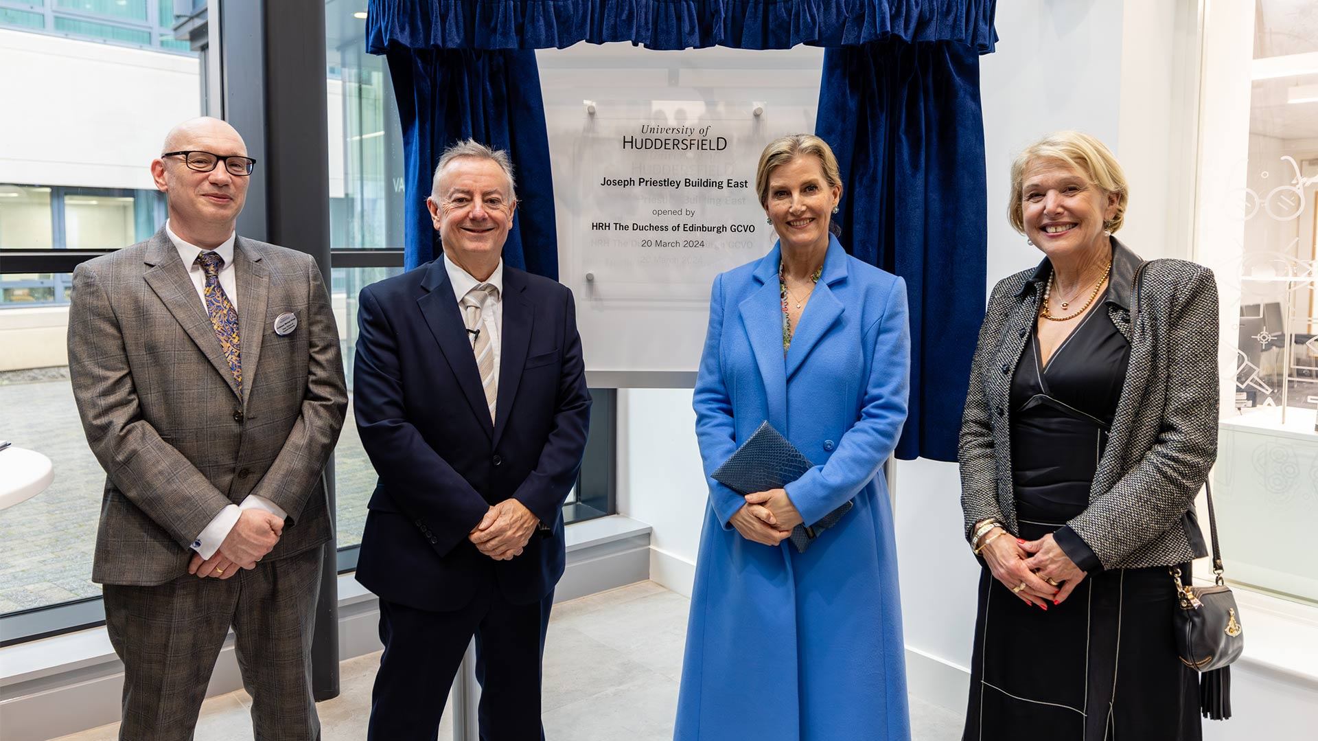 four people stood in front of a plaque