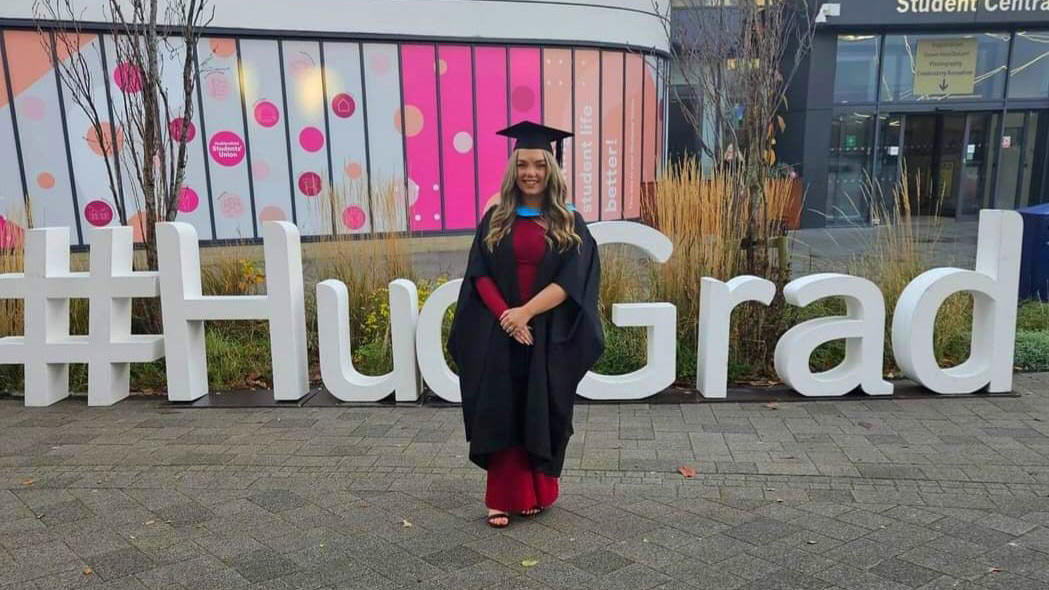 Joanne Charlton in front of a graduation sign