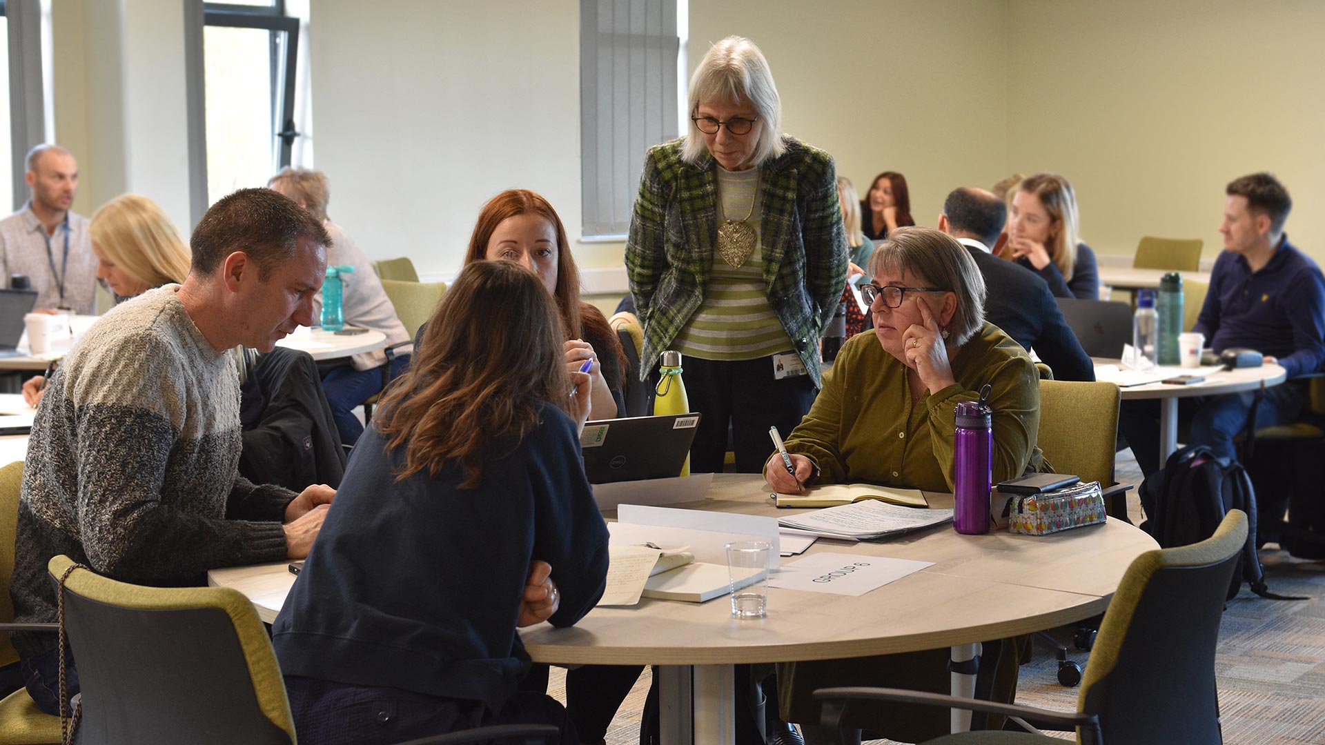 A lecturer talking to a group of students around a table