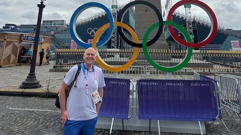 David Easson stands in front of the Olympic rings sign in Paris