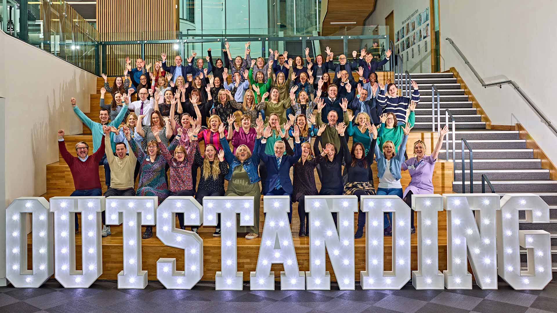A group of people celebrating with the word 'outstanding' in lights