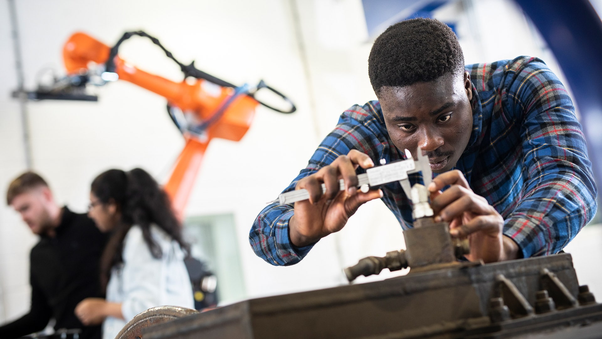 An Engineering student working with specialist equipment in a university facility. They are using a spanner like instrument to tighten something.