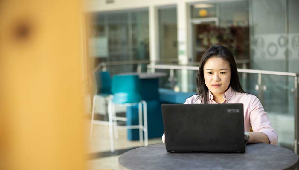 student on laptop at a table