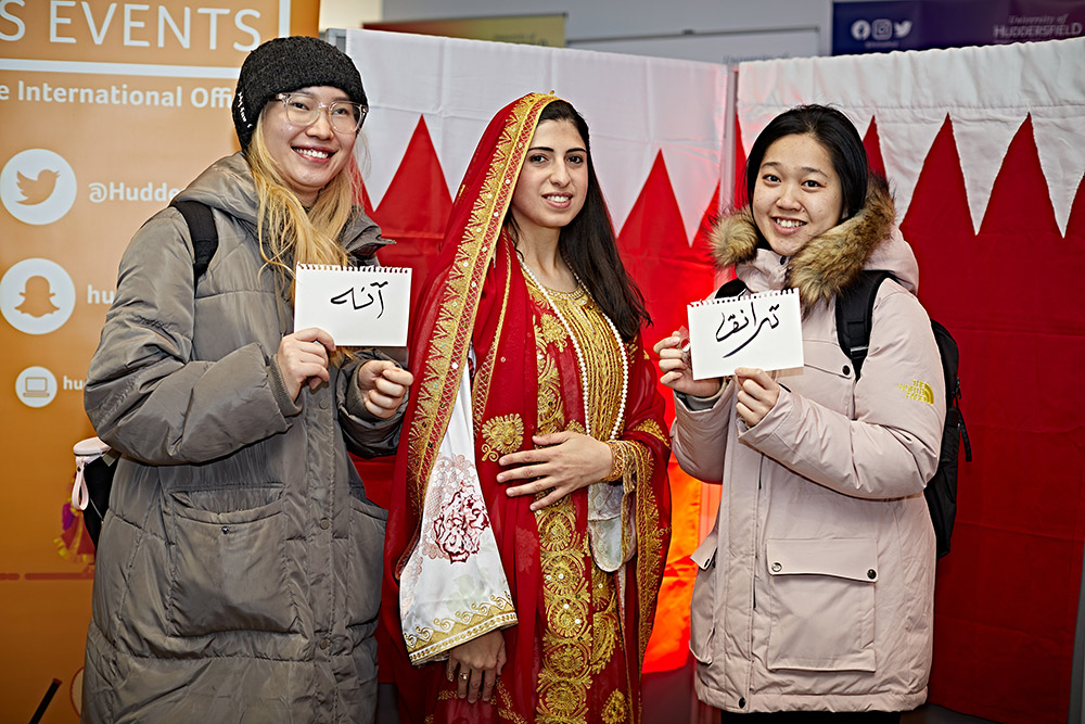 Three students stood together at the Bahrain National Day event.