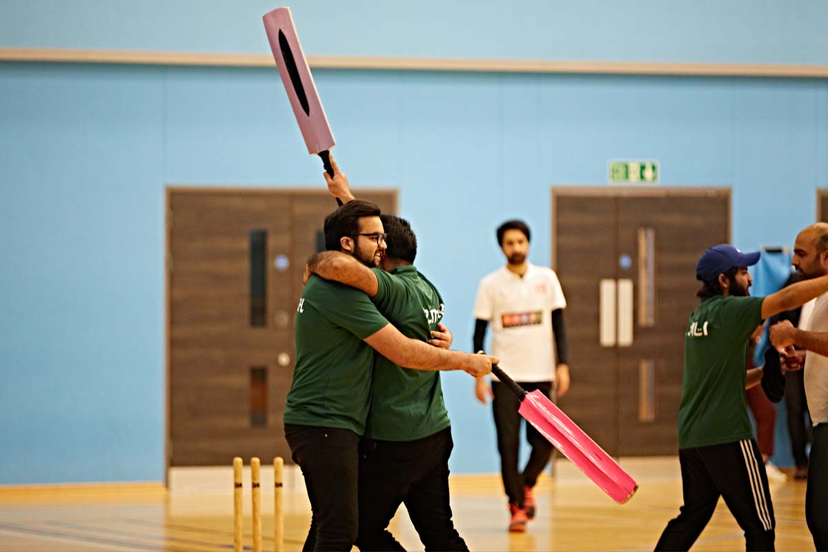 a photo of two students hugging and holding cricket bats