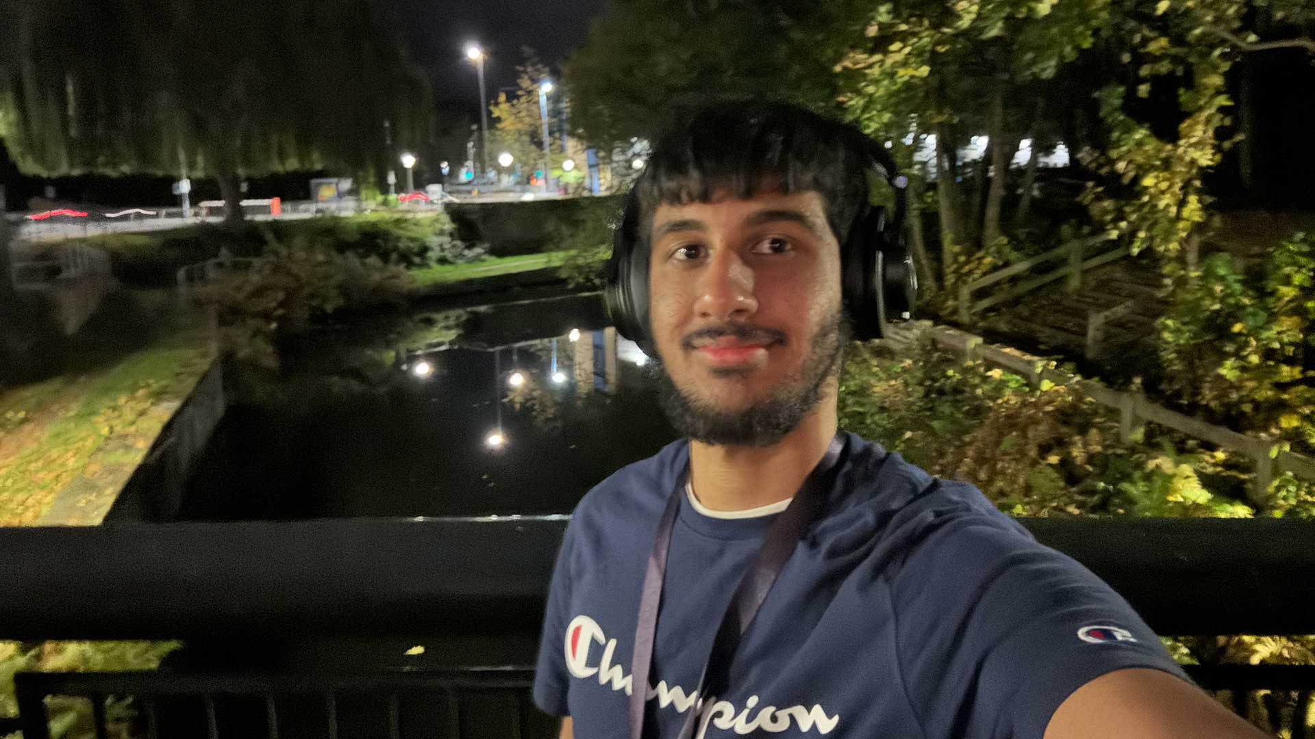 Edwin taking a selfie on the bridge over the campus the canal at night.
