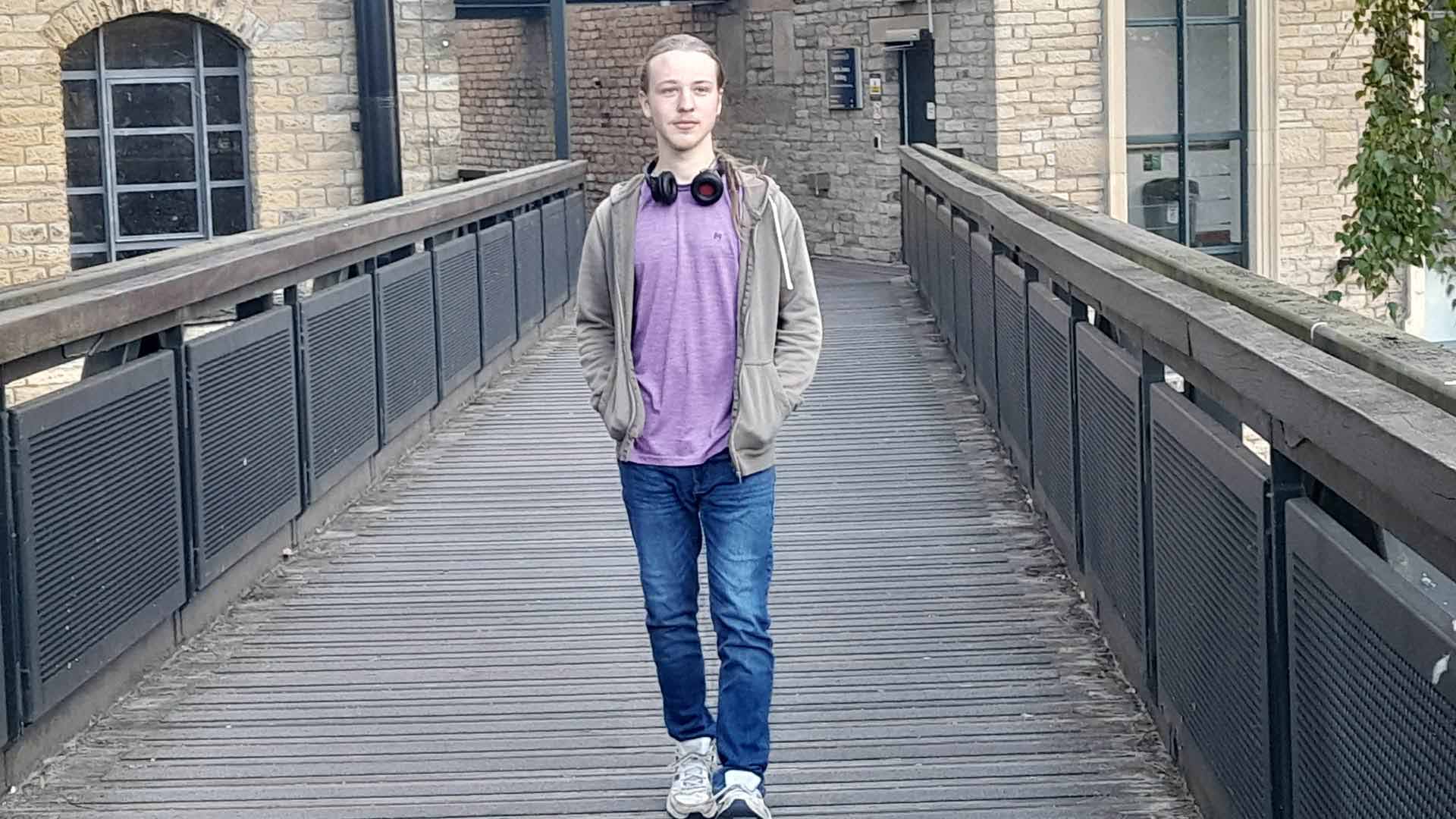 Nathan walking across a bridge on campus.